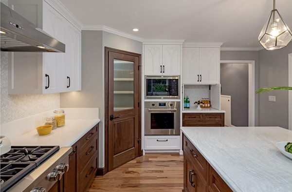 a modern kitchen remodel with white tulip-inspired cabinets and warm walnut drawers. from next stage design build remodeler