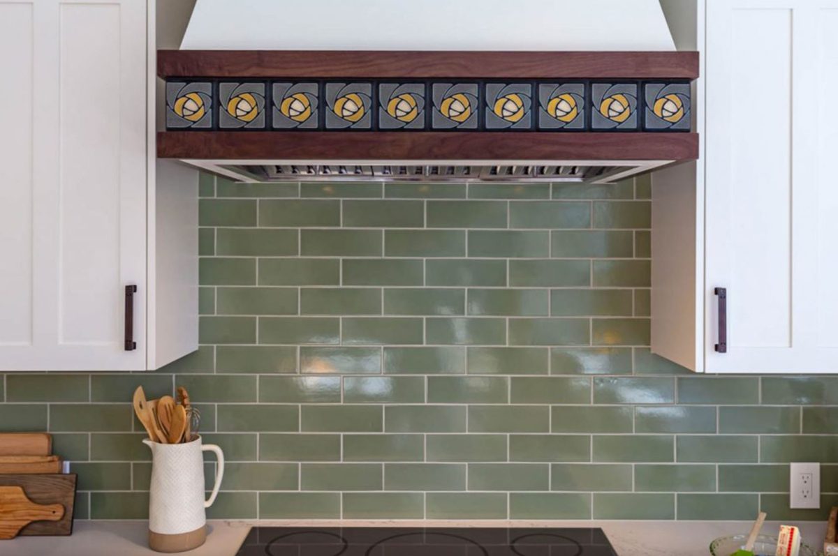 a colorful kitchen renovation can still be calming - this green subway tile feels cozy next to the decorative floral tiling on the range hood